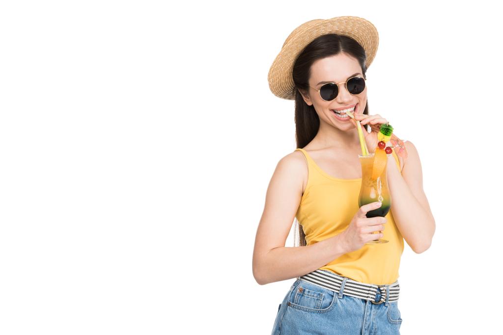 χαμογελαστό κορίτσι σε γυαλιά ηλίου και το καπέλο πίνοντας κοκτέιλ, απομονώνονται σε λευκό - Φωτογραφία, εικόνα
