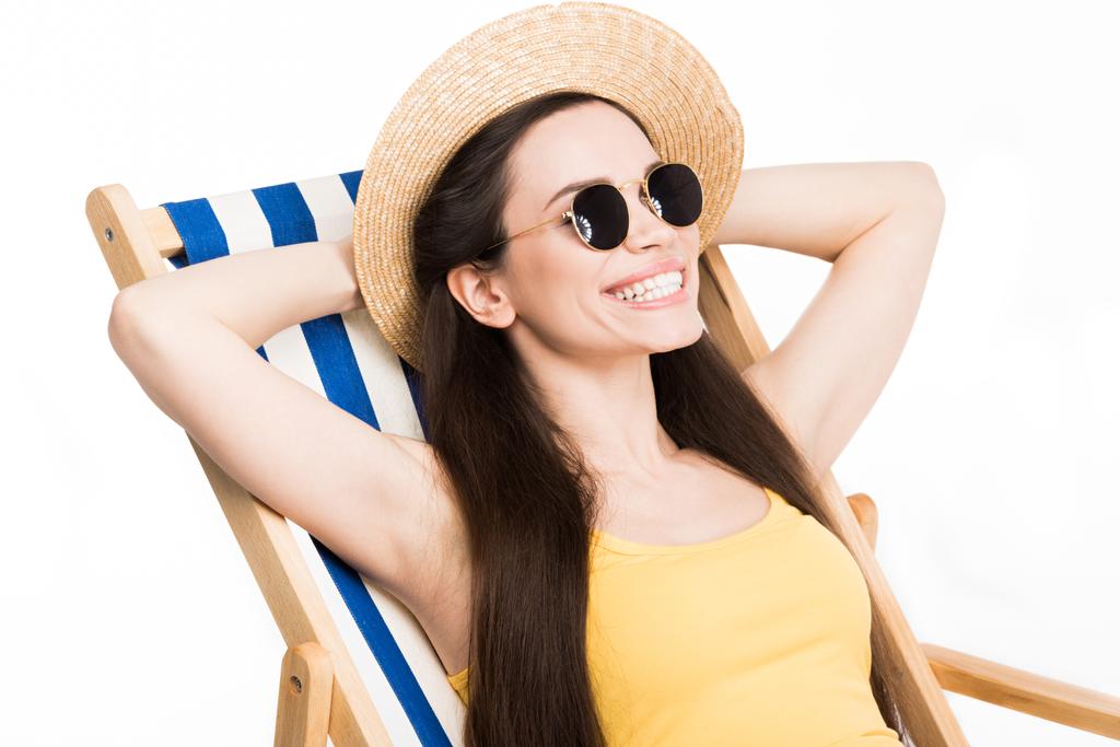 happy attractive girl in summer hat relaxing on beach chair, isolated on white - Photo, Image