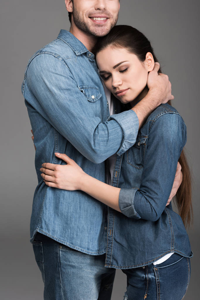 young couple in denim clothes embracing, isolated on grey - Photo, Image