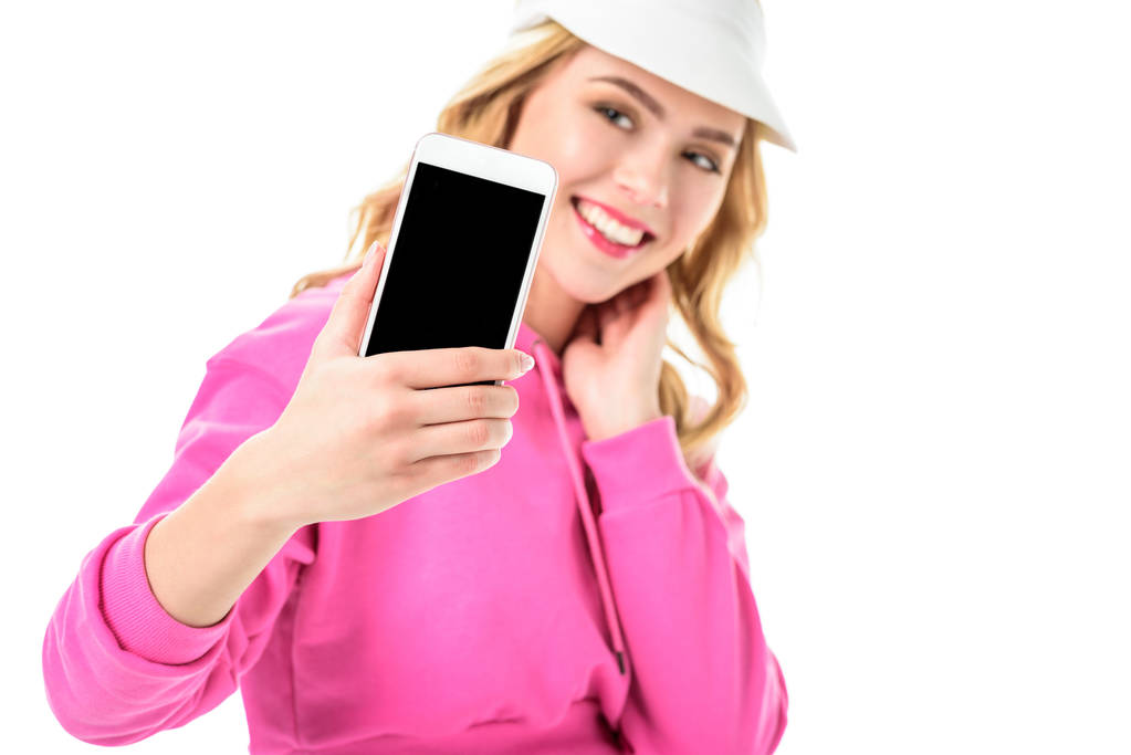 Szőke nő, rózsaszín ruhát és tenisz cap, vesz elszigetelt fehér selfie - Fotó, kép