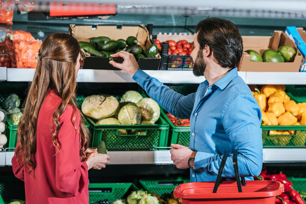 Rückansicht von Paar mit Einkaufskorb beim gemeinsamen Einkauf im Supermarkt - Foto, Bild