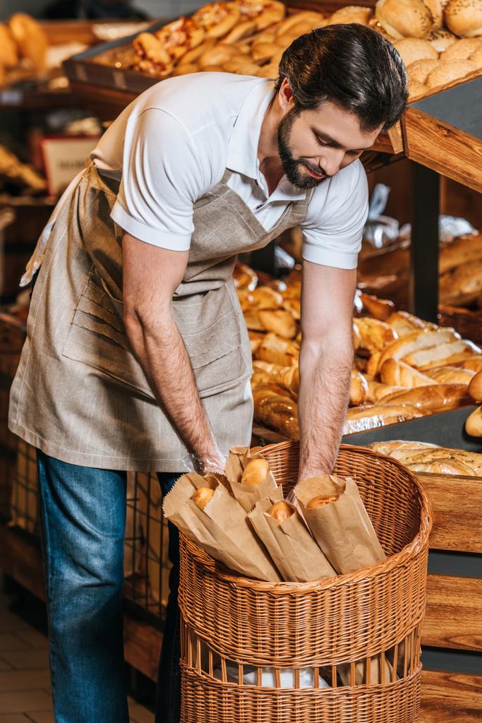 mannelijke winkelbediende schikken vers gebak in supermarkt - Foto, afbeelding
