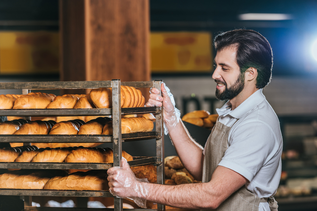 sorrindo assistente loja masculino organizar pastelaria fresca no supermercado
 - Foto, Imagem