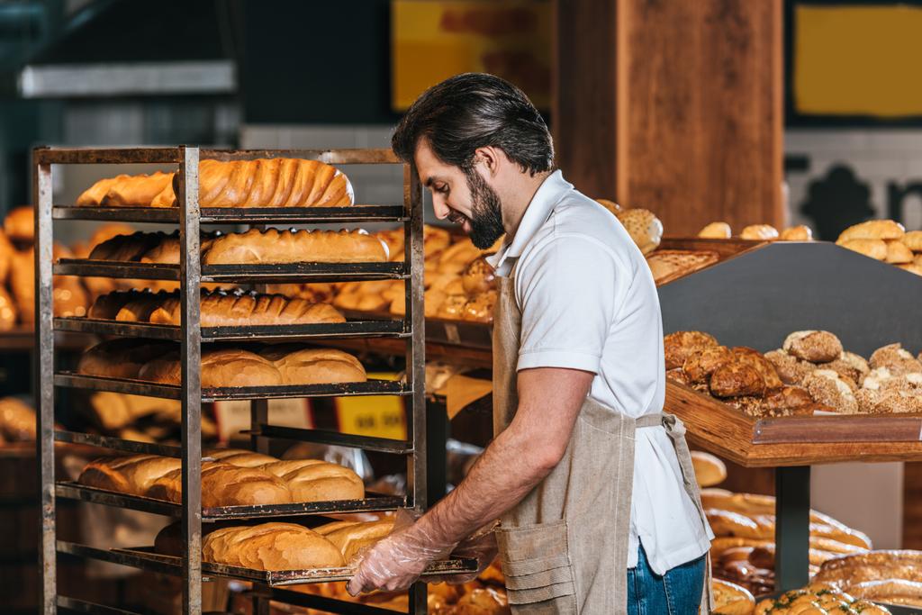 asistente de tienda masculino en delantal la organización de pastelería fresca en el supermercado
 - Foto, Imagen