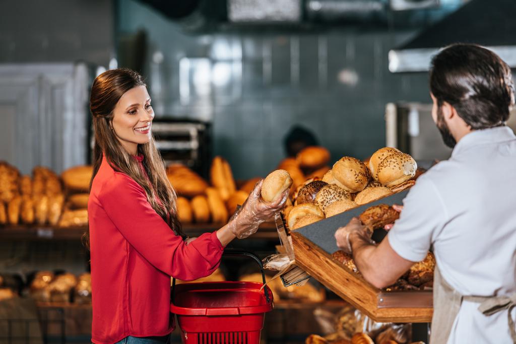 assistant de magasin donnant du pain à une femme avec panier dans un supermarché
 - Photo, image