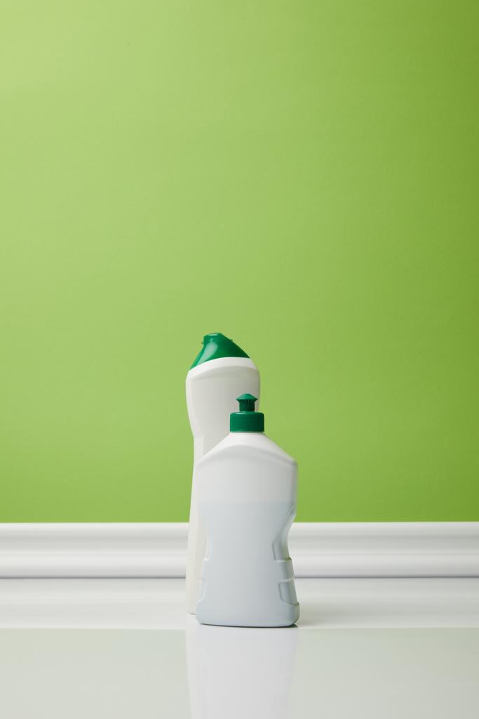 bottles with domestic supplies for spring cleaning on green - Photo, Image