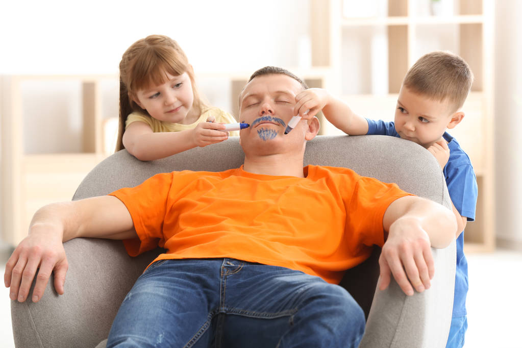 Les petits enfants peignent le visage de leur père pendant qu'il dort. Plaisanterie du jour d'avril
 - Photo, image
