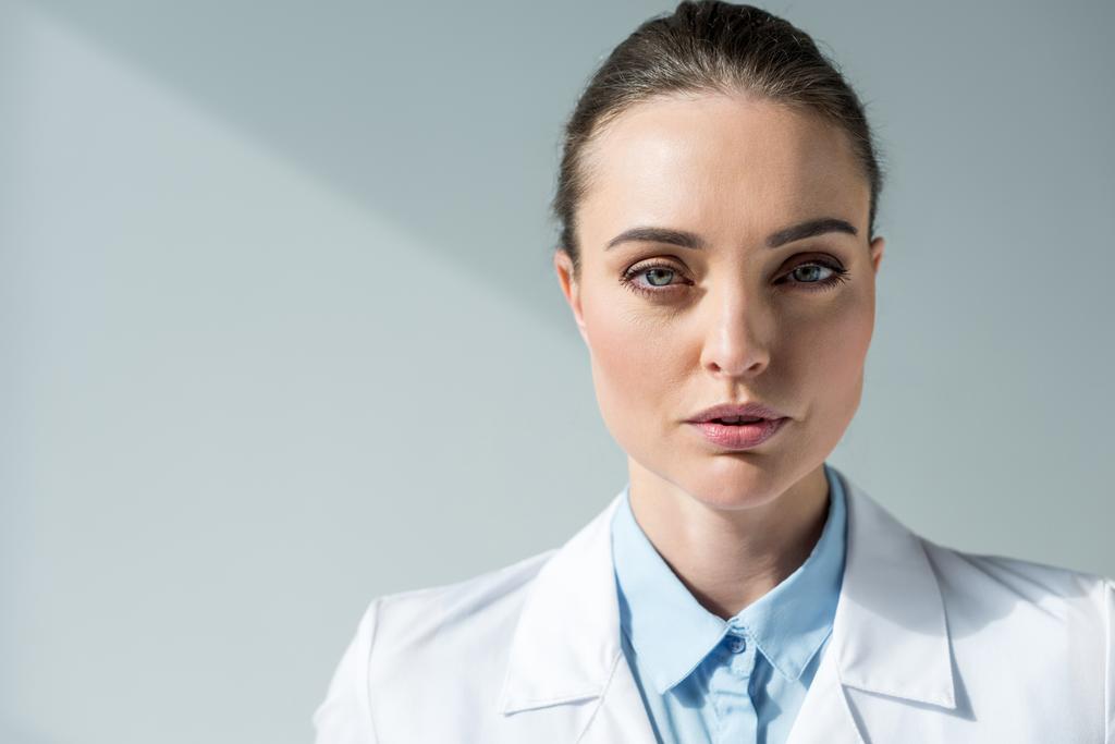 yakın çekim beyaz ceket gri kameraya bakarak ciddi kadın doktor portresi - Fotoğraf, Görsel