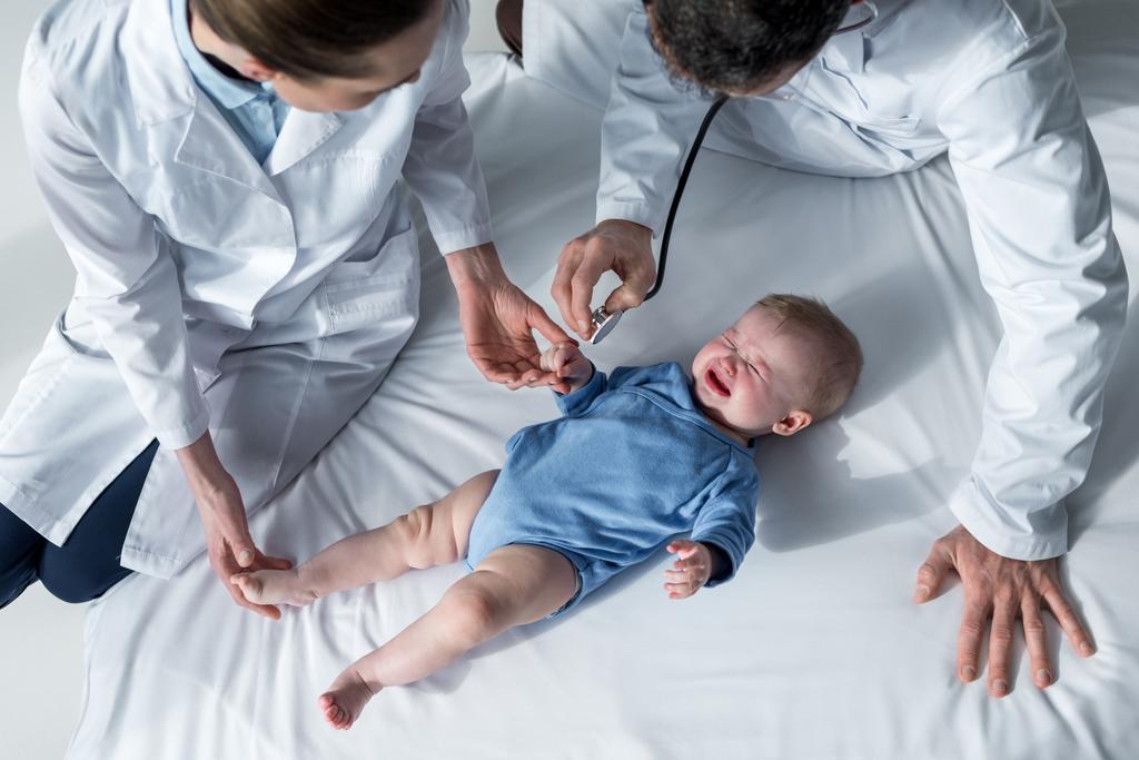 high angle view of pediatricians trying to check breath of crying baby - Photo, Image