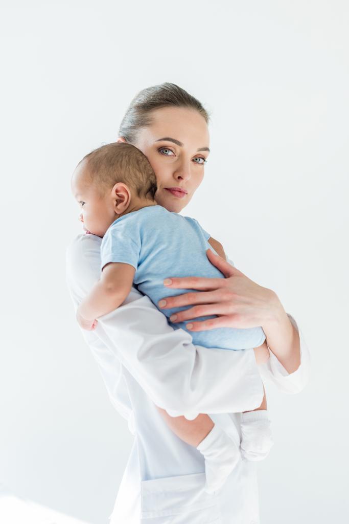 bela pediatra feminina carregando pequeno bebê isolado no branco
 - Foto, Imagem