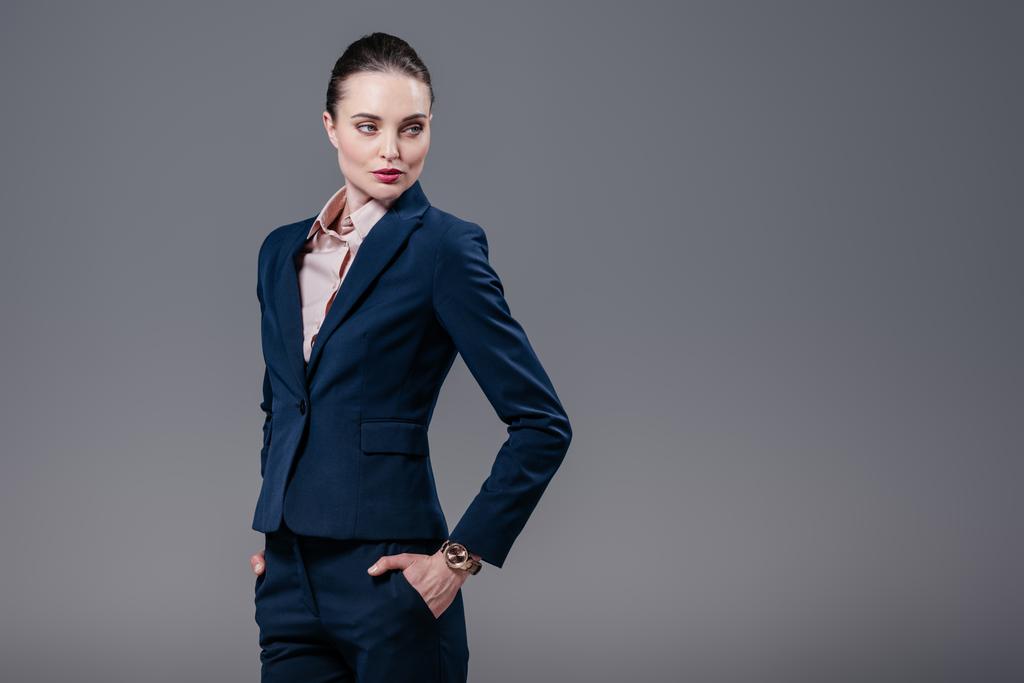 attractive adult businesswoman with hands in pockets looking away isolated on grey - Photo, Image