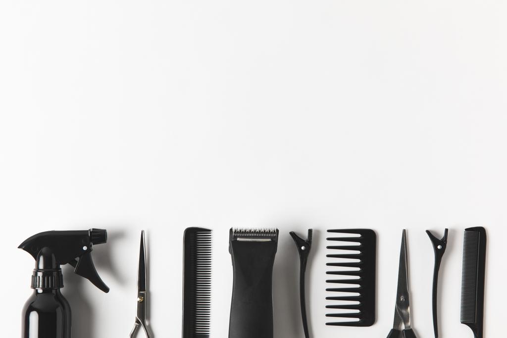 Draufsicht auf Haarschneidemaschine und Friseurwerkzeuge in Reihe, auf weiß - Foto, Bild