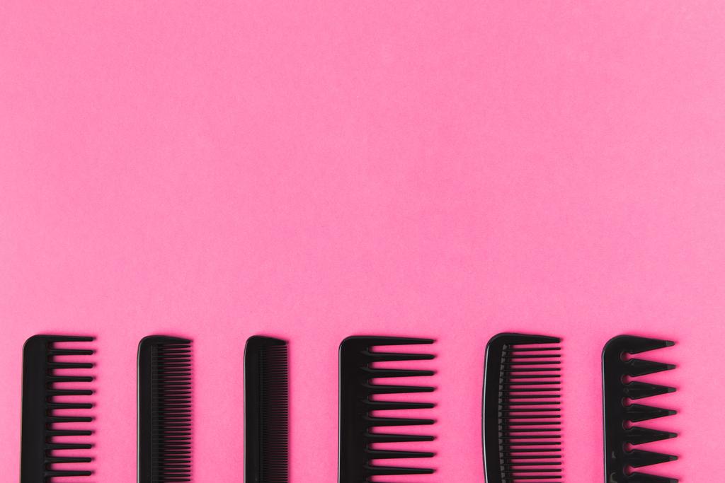 top view of black combs in row, isolated on pink with copy space - Photo, Image