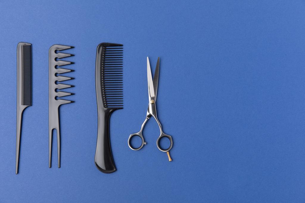flat lay with black hairbrushes and scissors, isolated on blue - Photo, Image