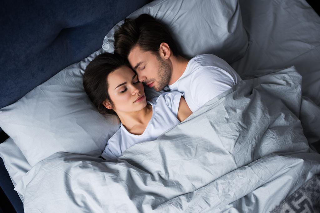 Homme barbu embrassant femme brune attrayante tout en dormant au lit
 - Photo, image