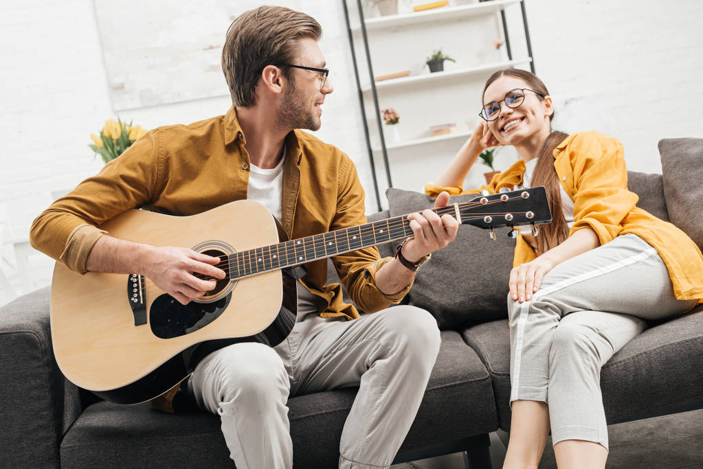 glücklicher junger Mann spielt Gitarre für glückliche Freundin - Foto, Bild