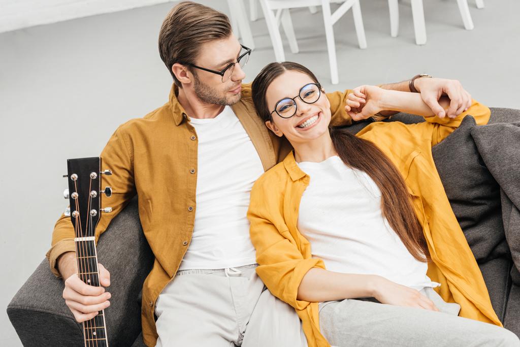 wysoki kąt widzenia szczęśliwa para z gitara siedzi na kanapie w domu - Zdjęcie, obraz