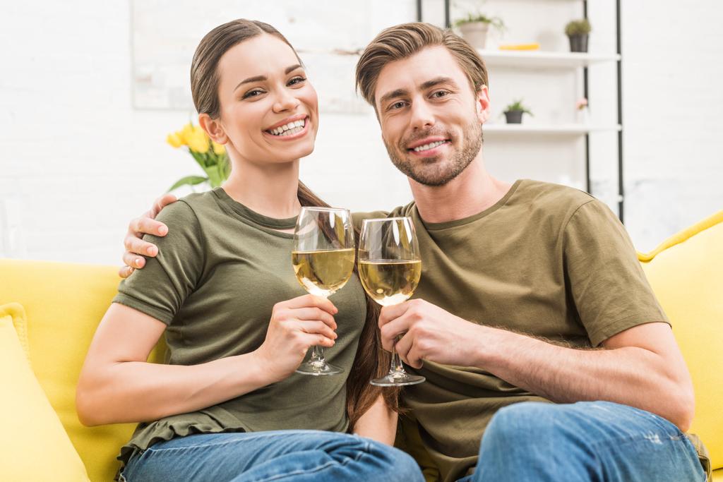 pareja tintineo con copas de vino en el sofá en casa
 - Foto, imagen