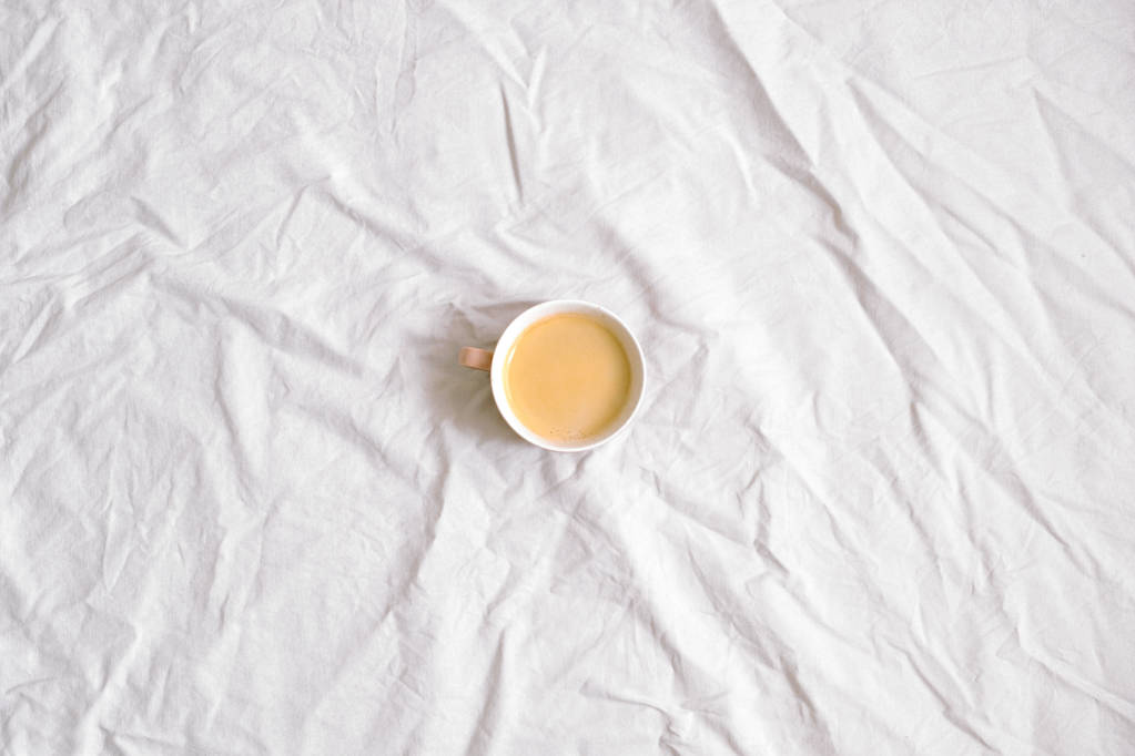 Šálek kávy na bílé bavlněné prostěradlo. Plochá ležel, horní pohled - Fotografie, Obrázek