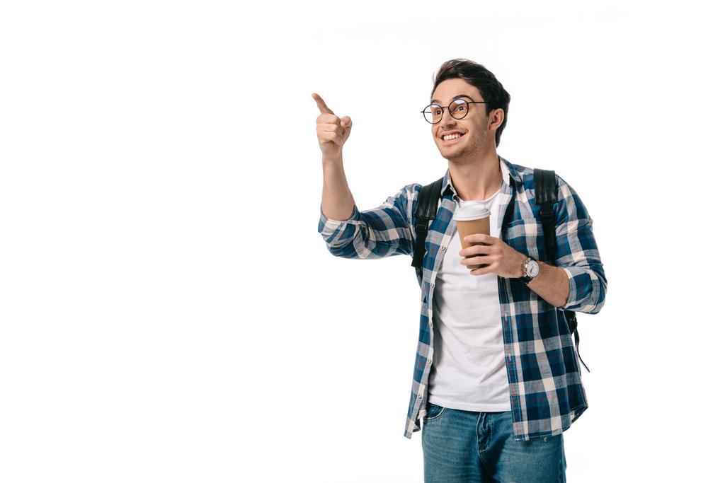 glückliche Studentin hält Kaffee in Pappbecher und zeigt auf etwas Isoliertes auf weißem Grund - Foto, Bild