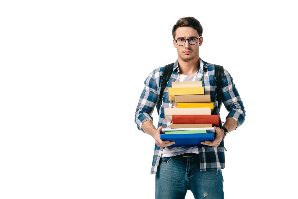 triste guapo estudiante sosteniendo pila de libros y mirando la cámara aislado en blanco
 - Foto, imagen