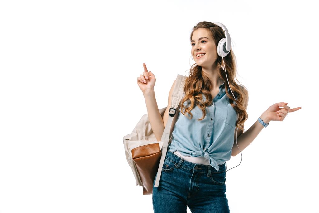 hermosa estudiante escuchando música con auriculares y bailando aislado en blanco
 - Foto, Imagen
