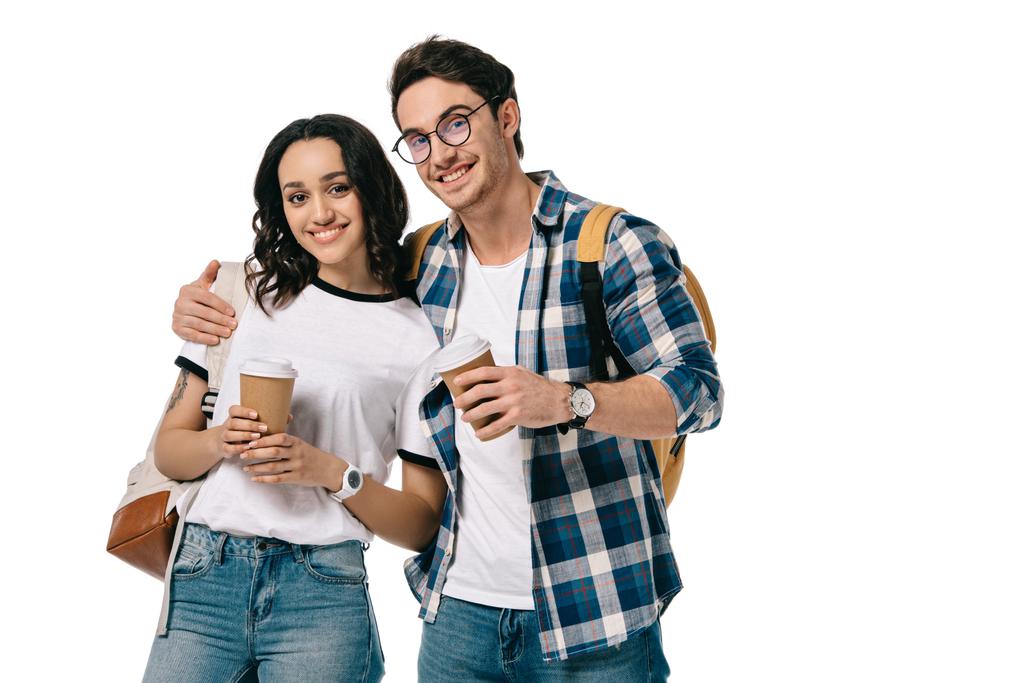 мультикультурные студенты обнимая и держа одноразовые чашки кофе изолированы на белом
 - Фото, изображение