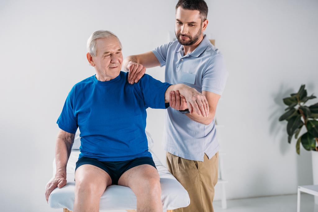 ritrattista terapeuta facendo massaggio all'uomo anziano sul lettino da massaggio
 - Foto, immagini