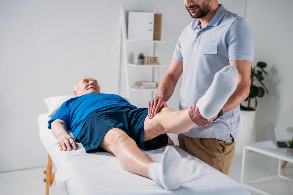 Masaj tablo bacaklarında kısmi fizyoterapist masaj üst düzey görünümünü mans - Fotoğraf, Görsel