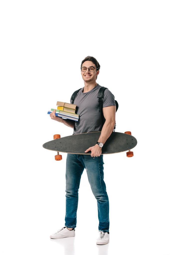 glimlachend knappe student bedrijf boeken en skate geïsoleerd op wit - Foto, afbeelding