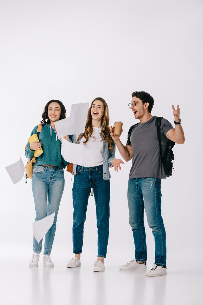 счастливые мультикультурные студенты смотрят на падающую бумагу на белом
 - Фото, изображение