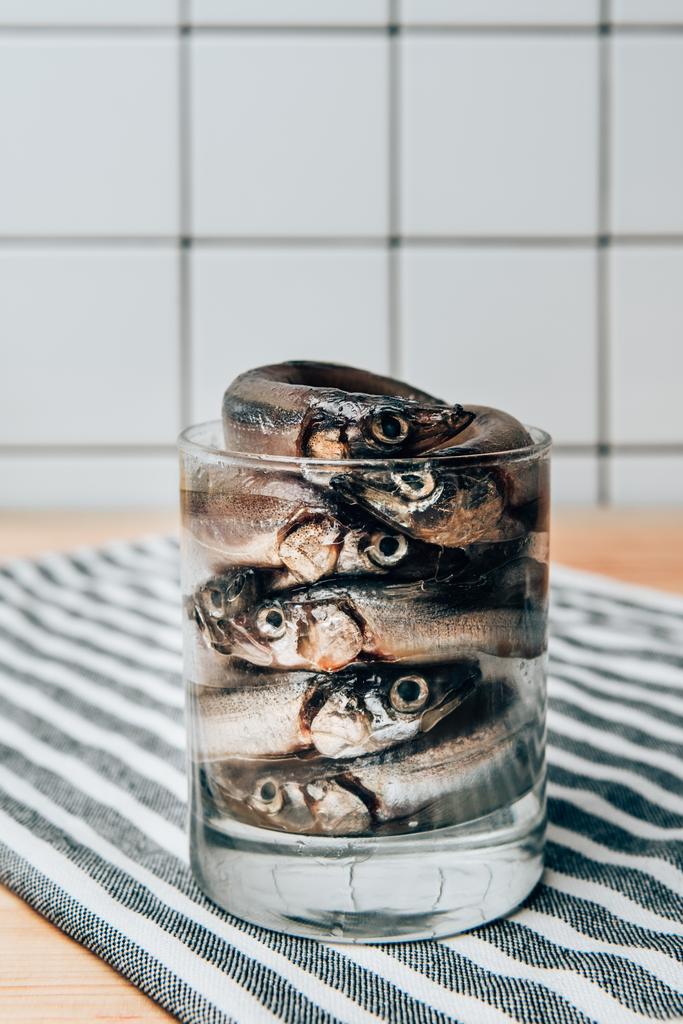 Vista frontal da pilha de peixe salgado em vidro na toalha
 - Foto, Imagem