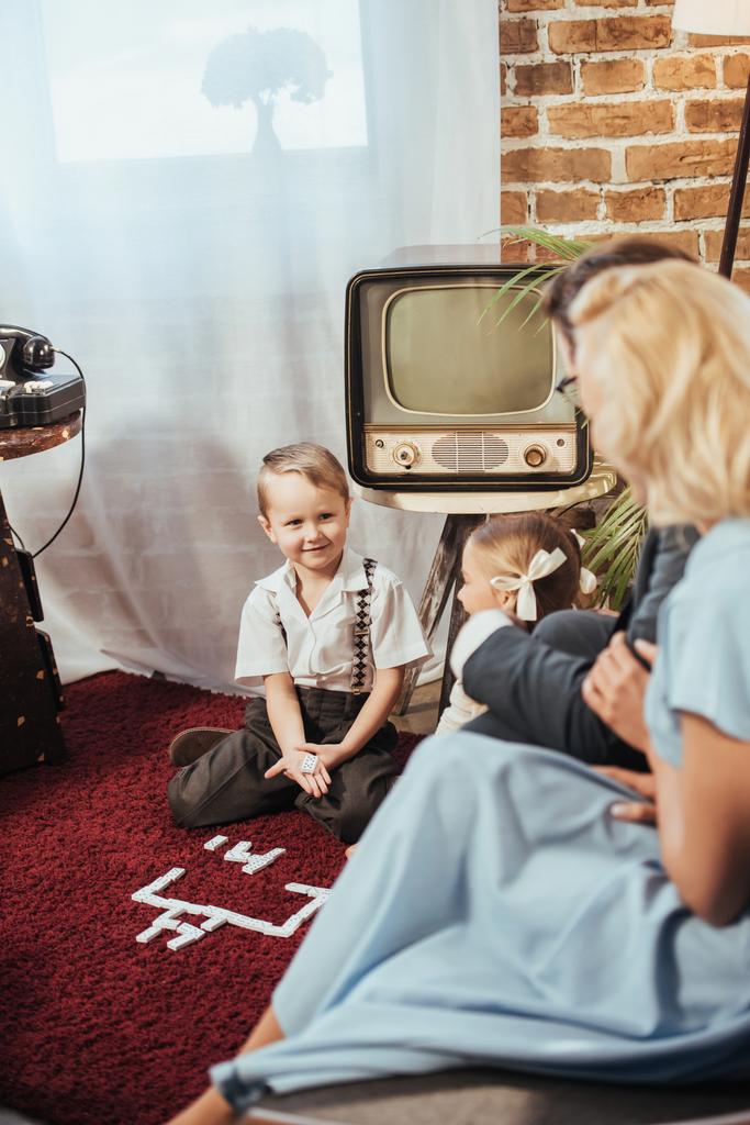 focalizzazione selettiva dei genitori che guardano bambini adorabili che giocano a casa, stile anni '50
  - Foto, immagini
