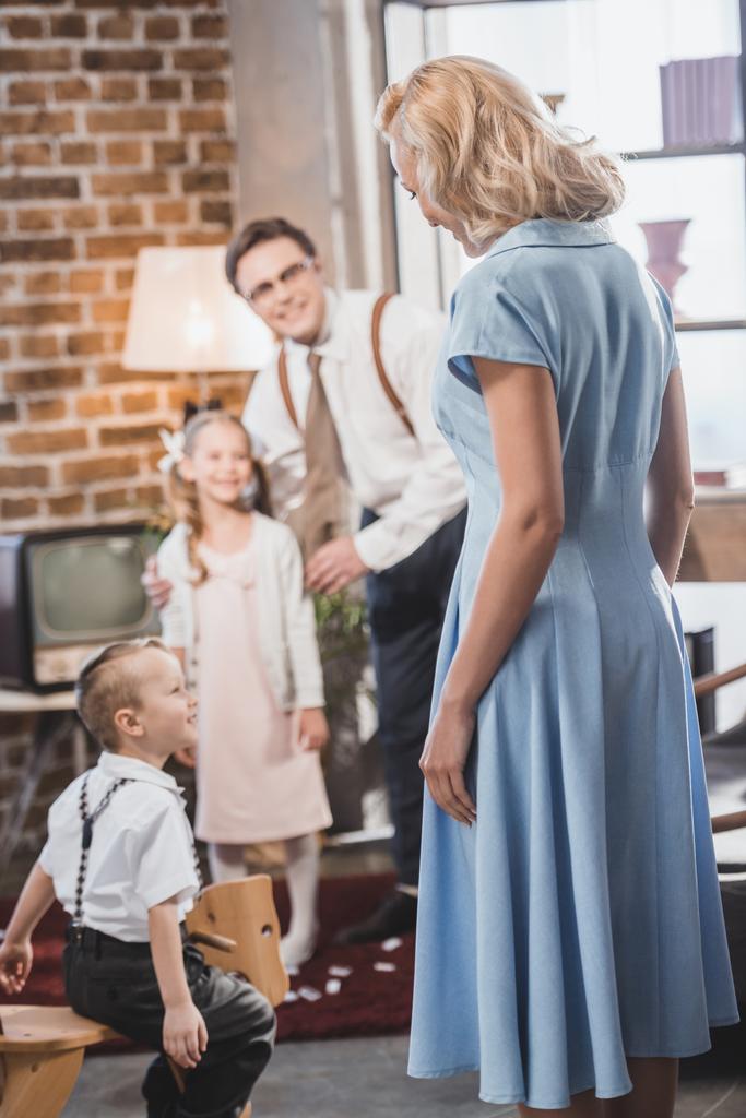 feliz 1950 homem e crianças olhando para mulher bonita em vestido azul em casa
 - Foto, Imagem
