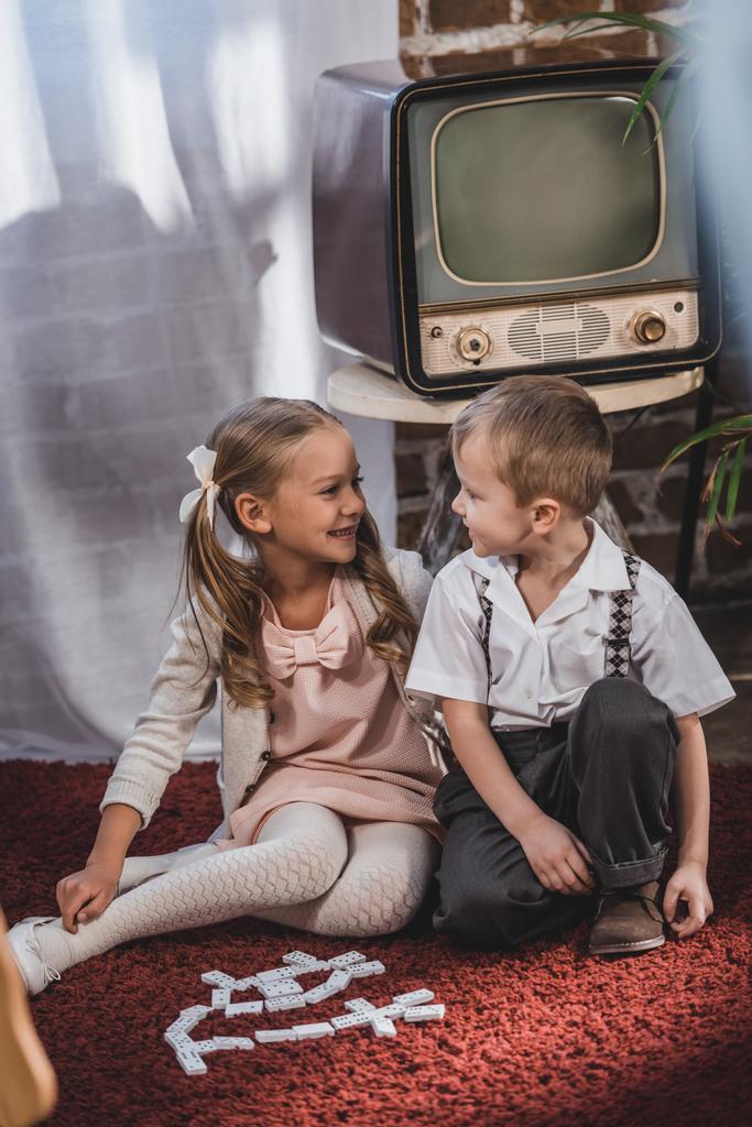 onnellisia pieniä lapsia 1950-luvulla tyyli vaatteita leikkii domino laatat kotona
 - Valokuva, kuva