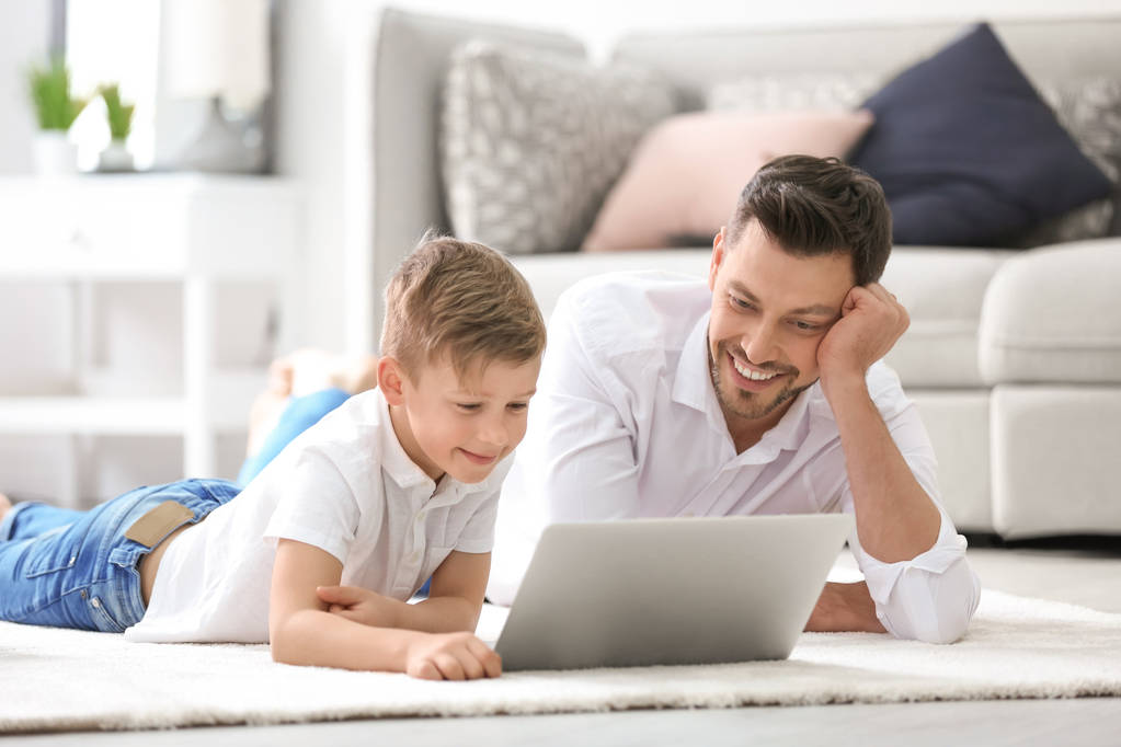 Μικρό αγόρι και ο μπαμπάς του χρησιμοποιώντας το φορητό υπολογιστή στο σπίτι - Φωτογραφία, εικόνα