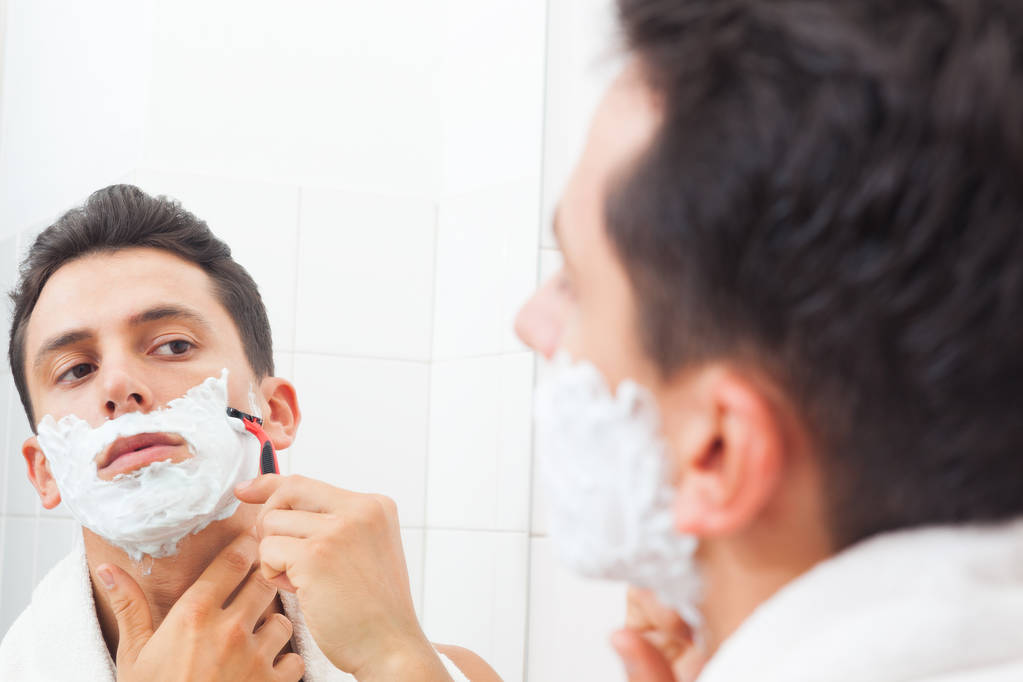 Kaveri ajelee partansa partaveitsellä kylpyhuoneessa
 - Valokuva, kuva