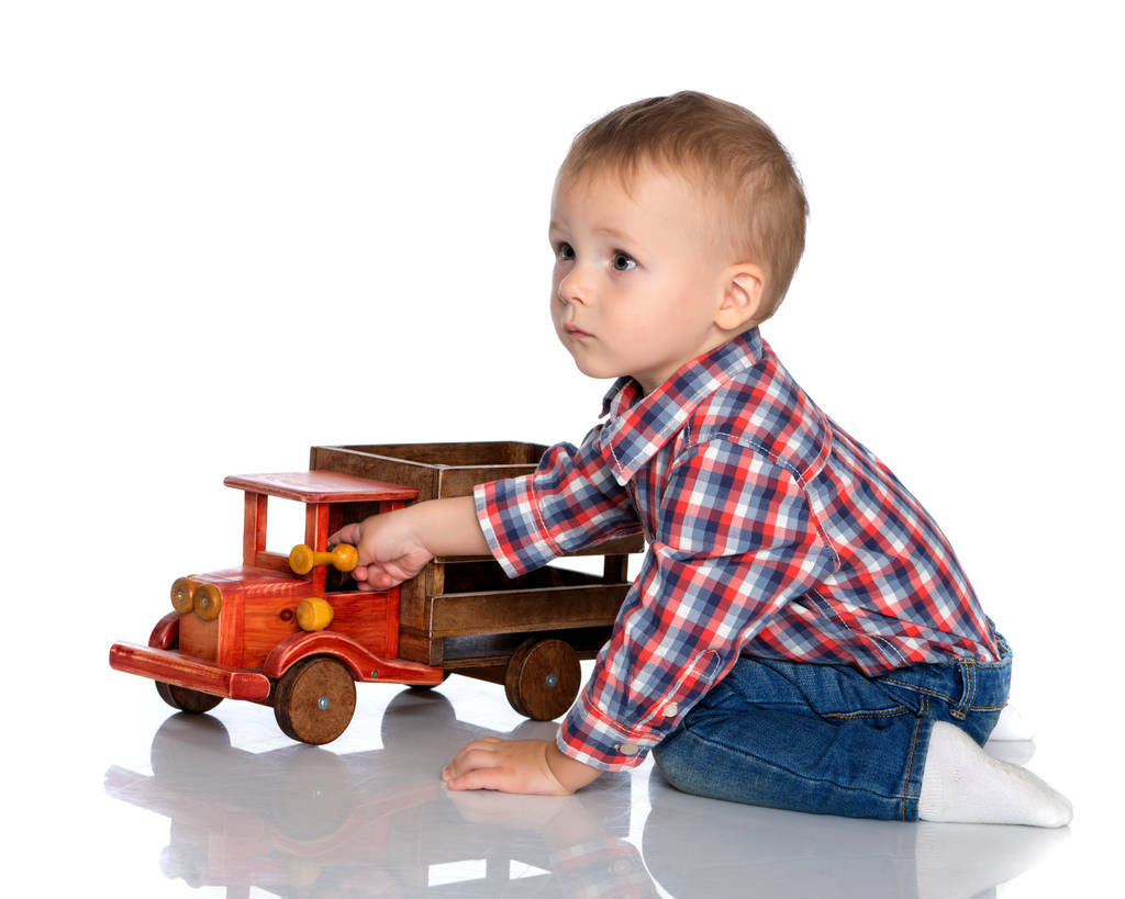 Mały chłopiec bawi się zabawkowym samochodem.. - Zdjęcie, obraz
