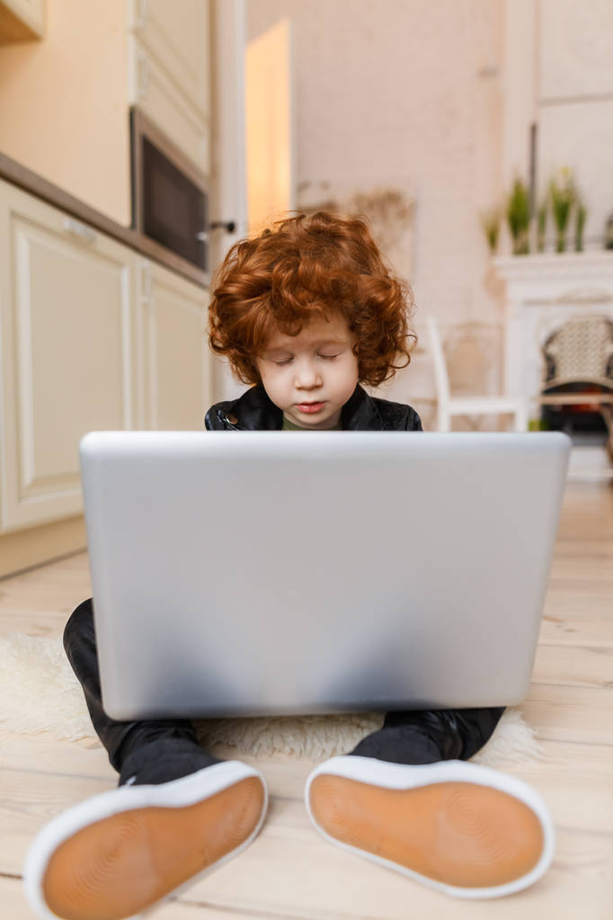 Маленький рудий хлопчик використовує ноутбук
 - Фото, зображення