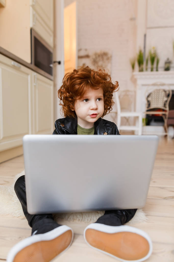 Kleine roodharige jongen maakt gebruik van een laptop - Foto, afbeelding