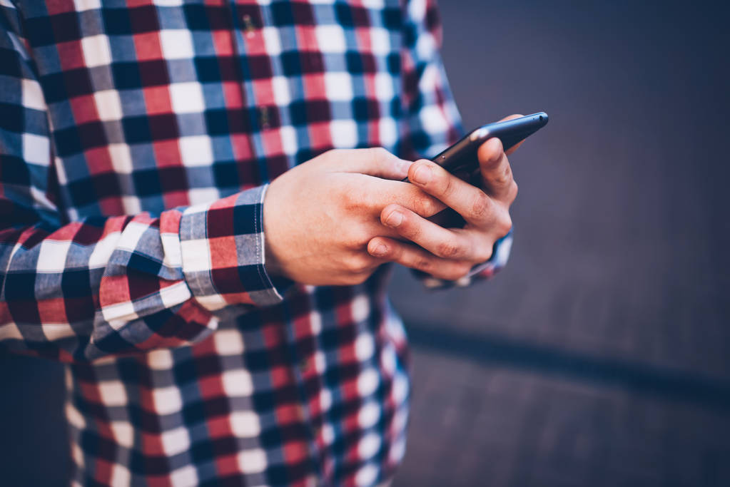 Обрезанное изображение мужчины в клетчатой рубашке с помощью смартфона, загружающего мультимедийные файлы из социальных сетей, руки мужчины, держащего современные мобильные телефоны, отправляющие сообщения в чате с друзьями онлайн
 - Фото, изображение