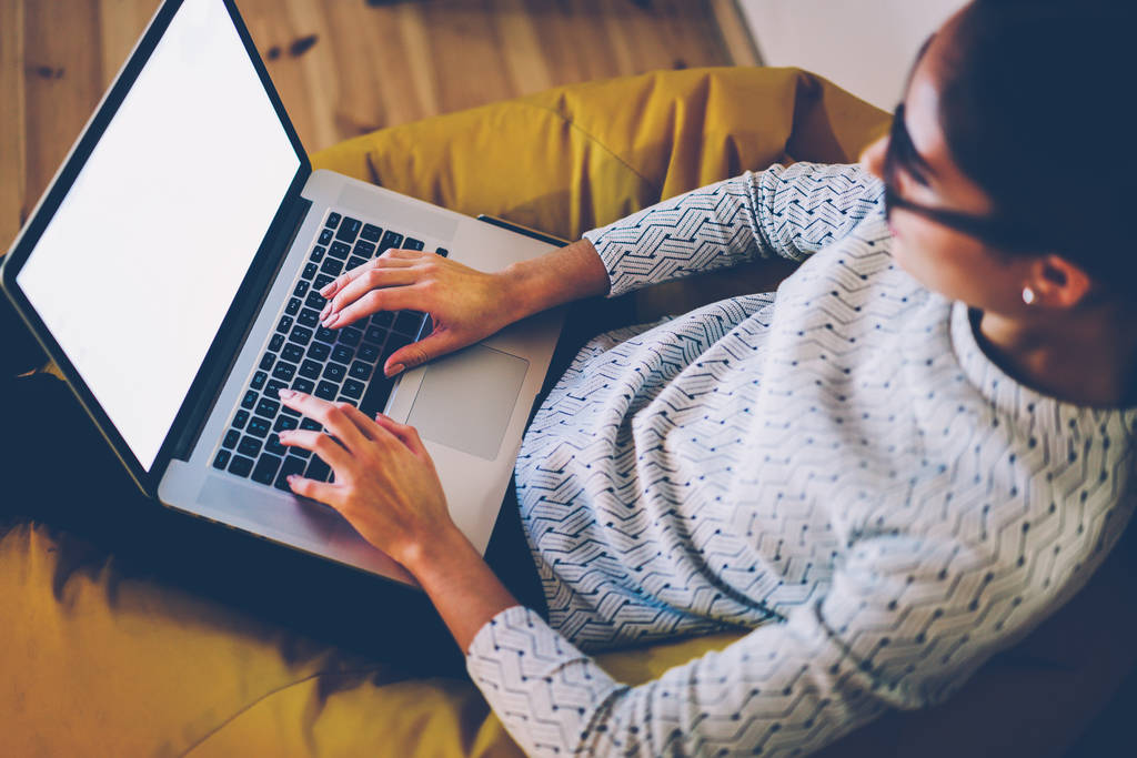 女性フリーランサー距離コワーキング オフィスで仕事をしている web ページ上の文書をキーボード入力画面モックアップのネットブックを使用してラップトップ コンピューターをオンラインで情報を検索で入力する女性のトップ ビュー - 写真・画像
