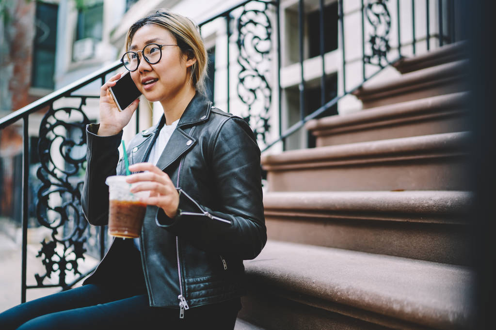 Vážné mladé Asijské žena v brýlí kontrola bankovní účet během mobilní konverzaci s vkladní ledová káva jít, Čínská dívka sedící na schodech mluví s přítelem na telefonu - Fotografie, Obrázek