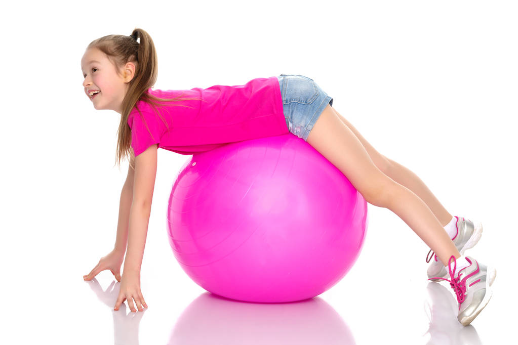 bambina che fa esercizi su una palla grande per idoneità. - Foto, immagini