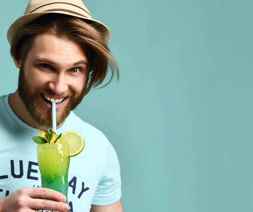 Mladý muž v klobouku pití margarita koktejl pít šťávy radost při pohledu na fotoaparát  - Fotografie, Obrázek
