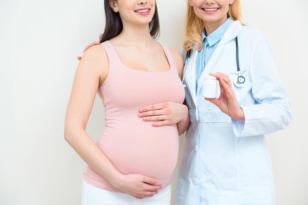 産科婦人科医と薬の瓶を保持している妊娠中の女性のショットはトリミング - 写真・画像