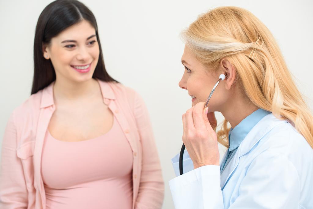 крупним планом знімок акушер-гінеколога, що слухає серцебиття дитячого плоду вагітної жінки зі стетоскопом
 - Фото, зображення