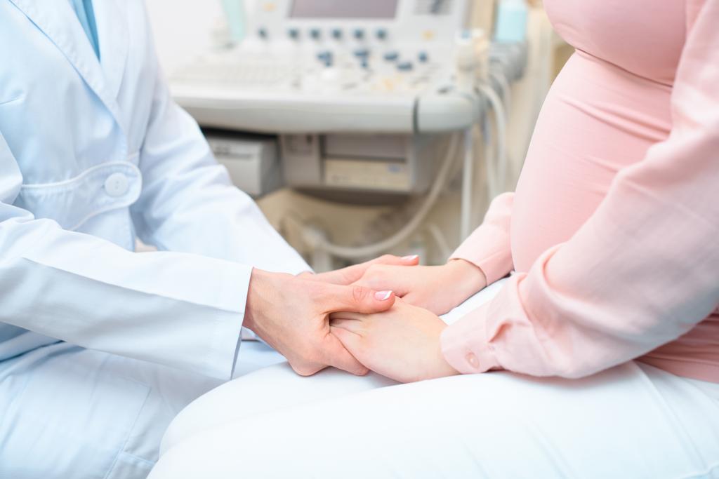 rajattu laukaus synnytyslääkäri gynekologi kädestä raskaana olevan naisen
 - Valokuva, kuva