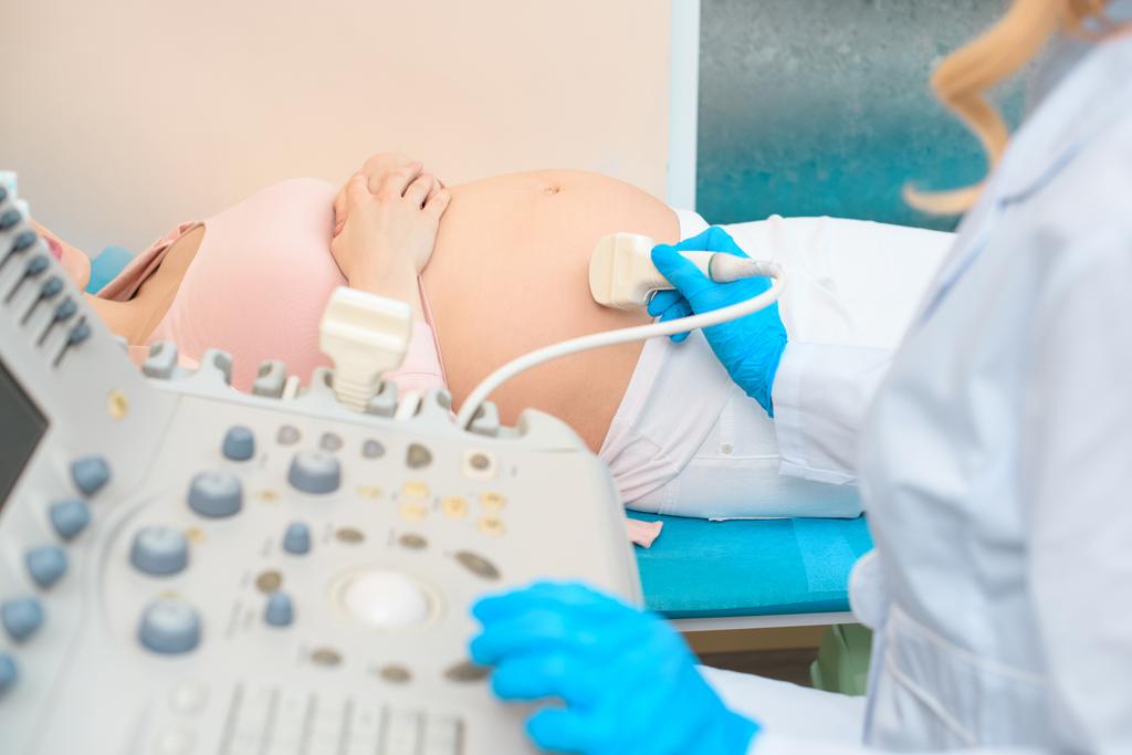 tiro recortado de ginecologista obstetra fazendo ultra-som de digitalização para a mulher grávida
 - Foto, Imagem