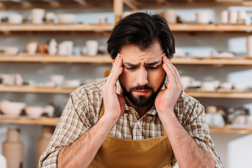 moe mannelijke potter hoofdpijn hebben tijdens de vergadering in werkplaats - Foto, afbeelding